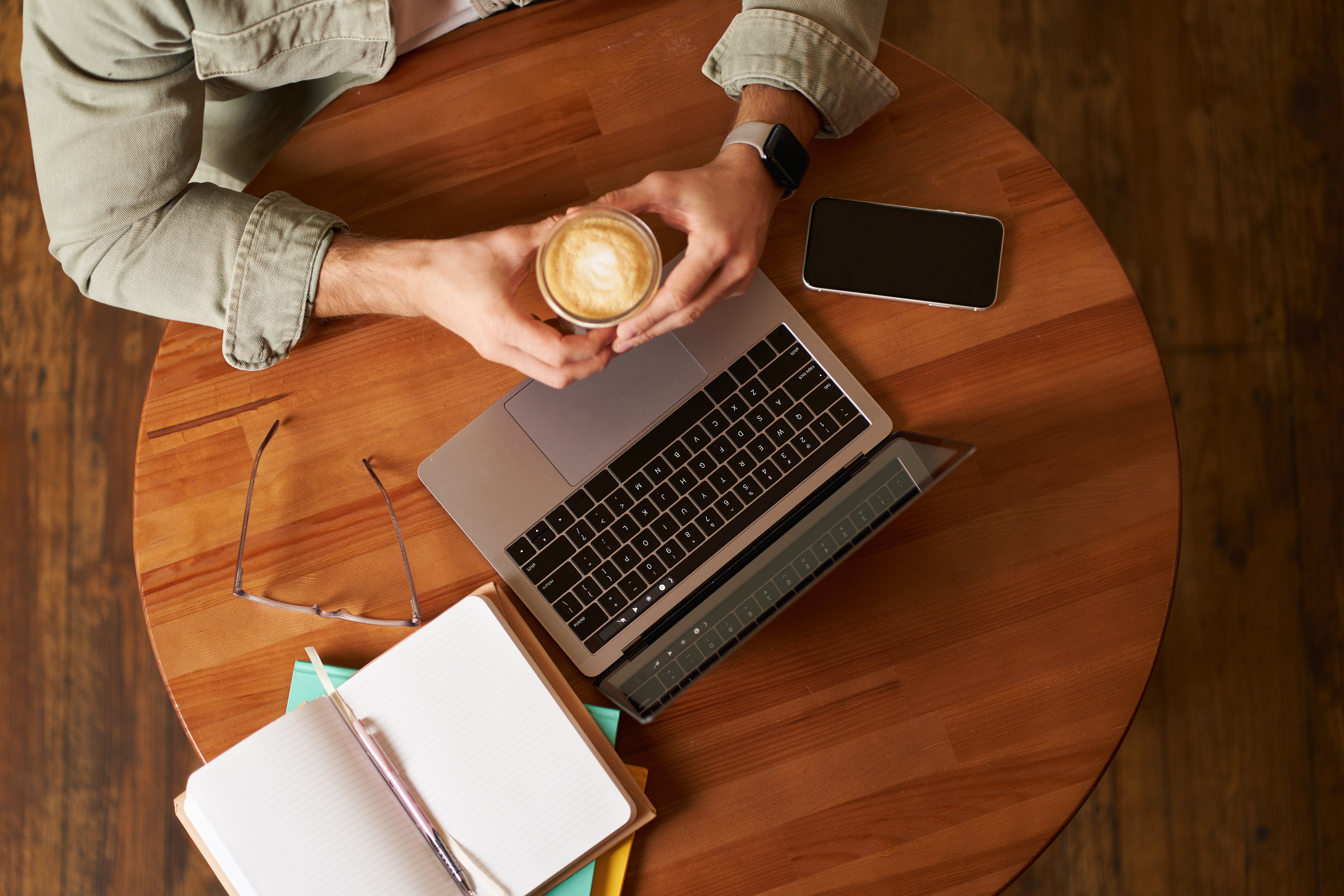 top-view-male-hands-holding-cup-coffee-man-sitting-round-table-cafe-working-laptop-had