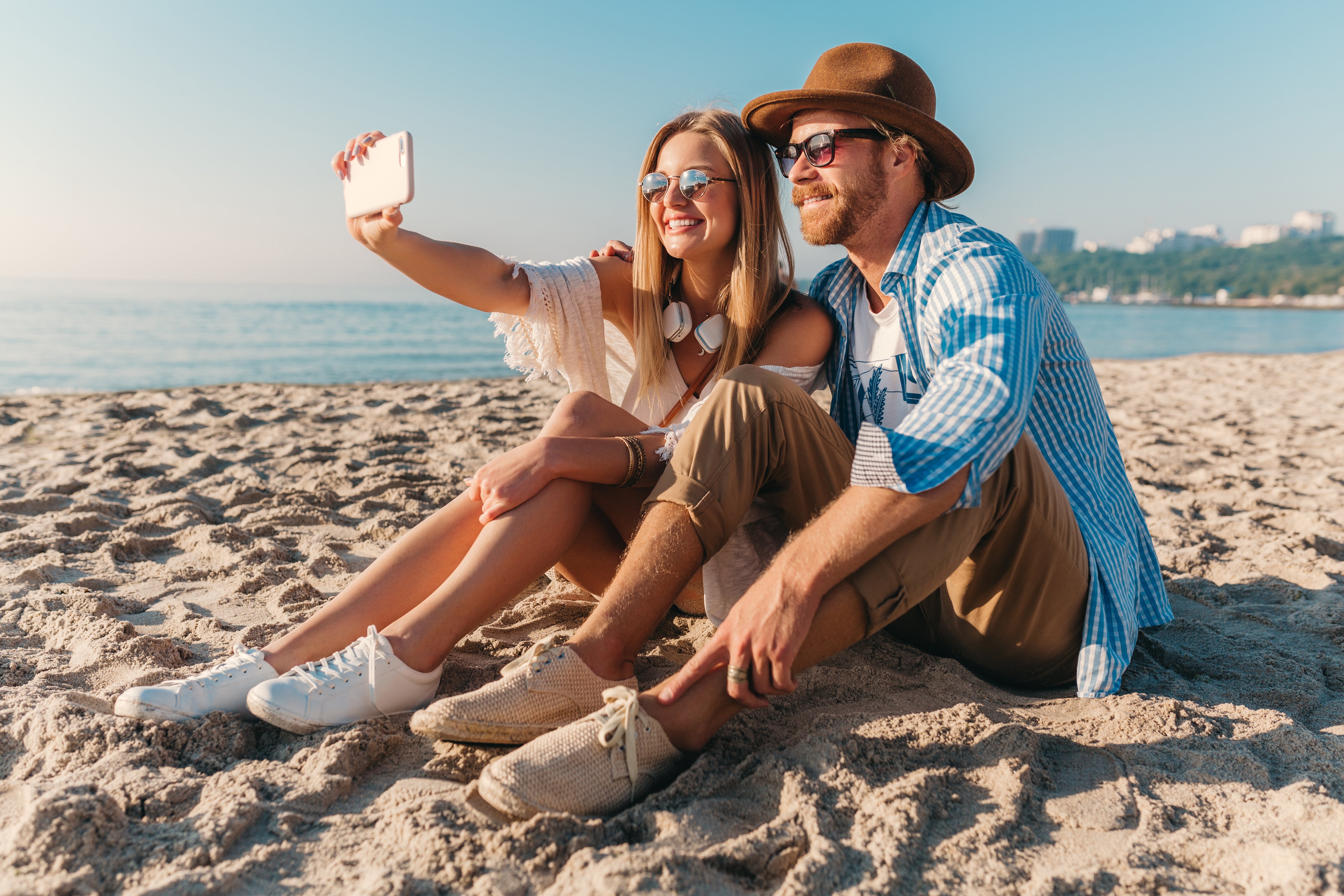 young-attractive-smiling-happy-man-woman-sunglasses-sitting-sand-beach-taking-selfie-photo